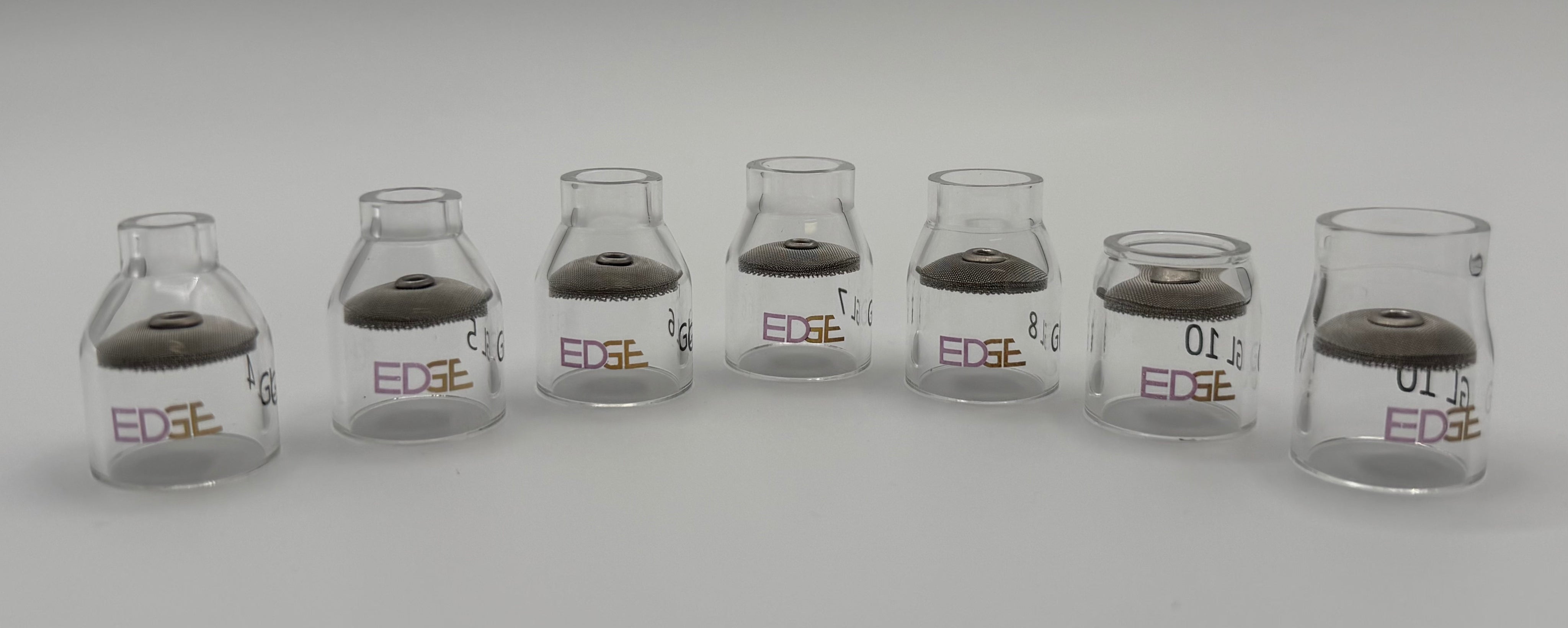 Row of clear glass EDGE welding cups with mesh diffusers on white background