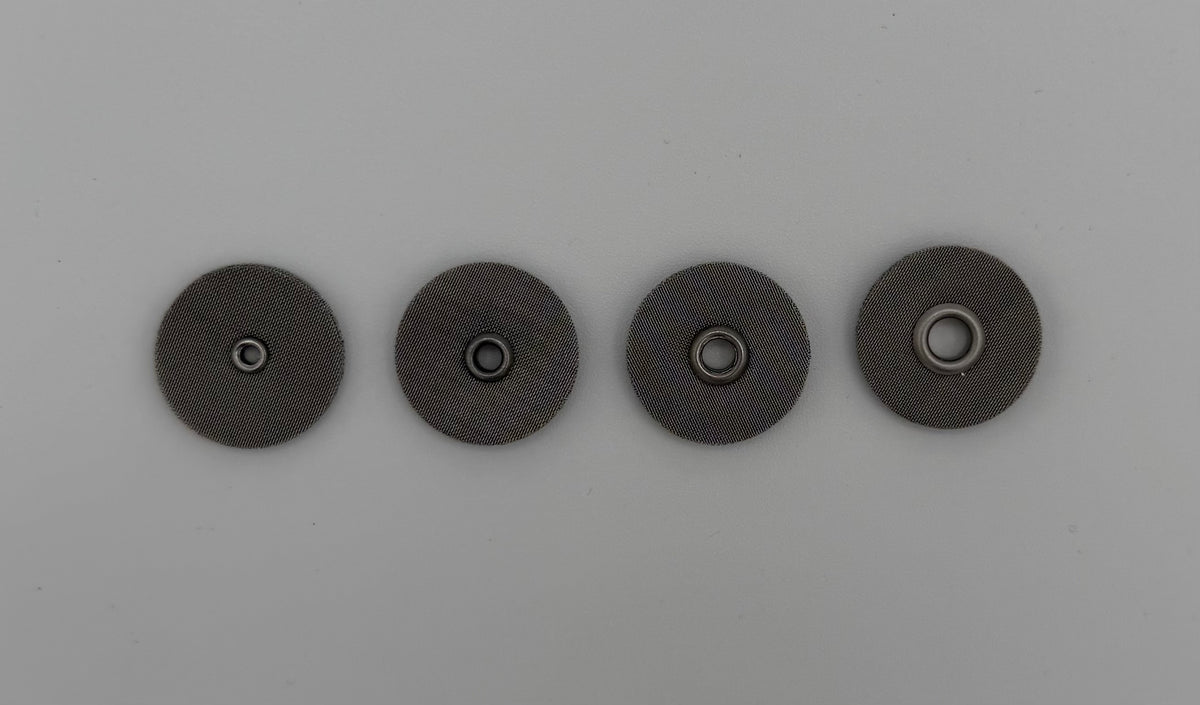 Four round stainless steel welding cup screens with central holes on a light background