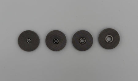 Four round stainless steel welding cup screens with central holes on a light background