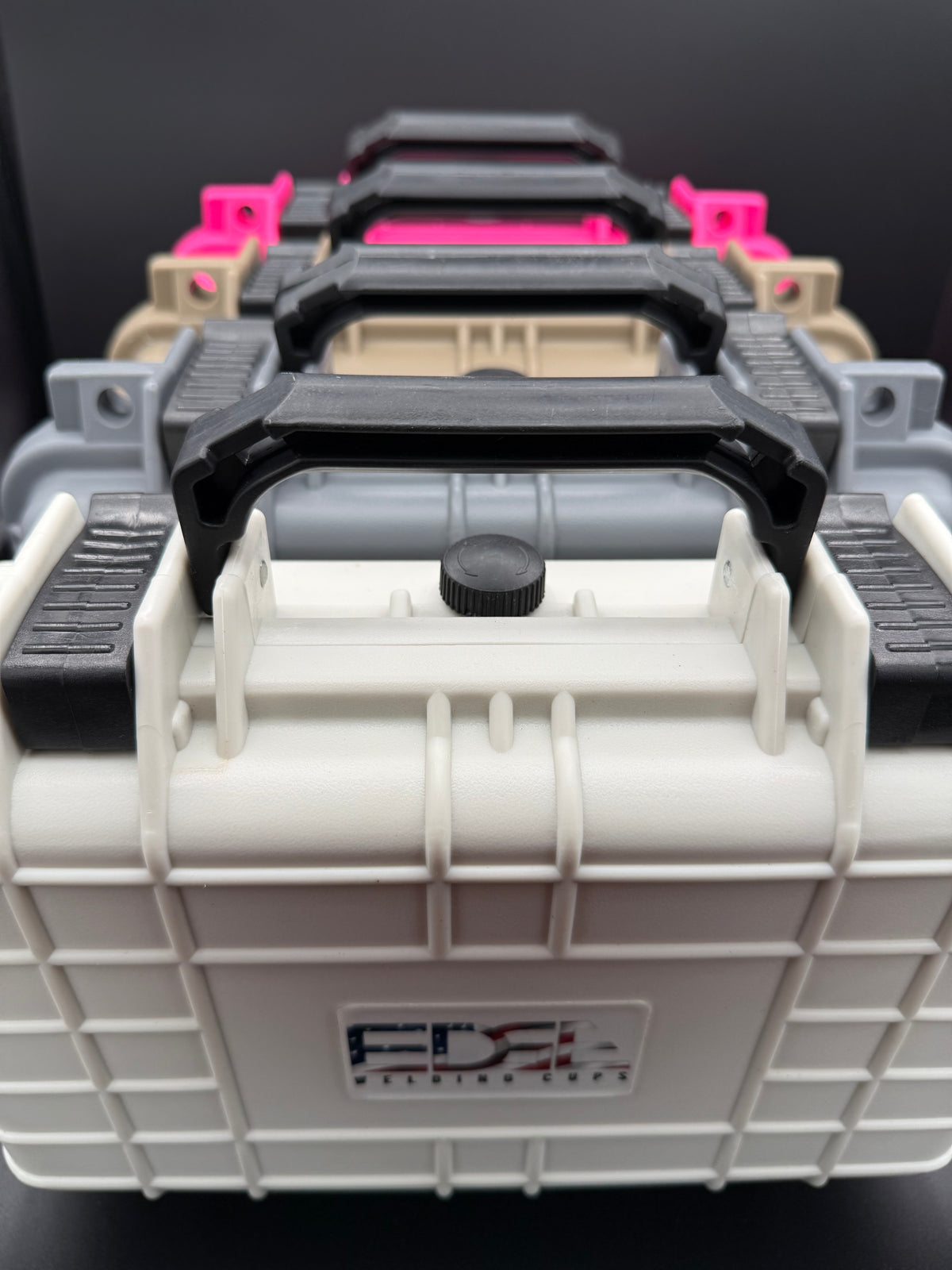 Stacked hard plastic tool cases with black handles in multiple colors, viewed close-up
