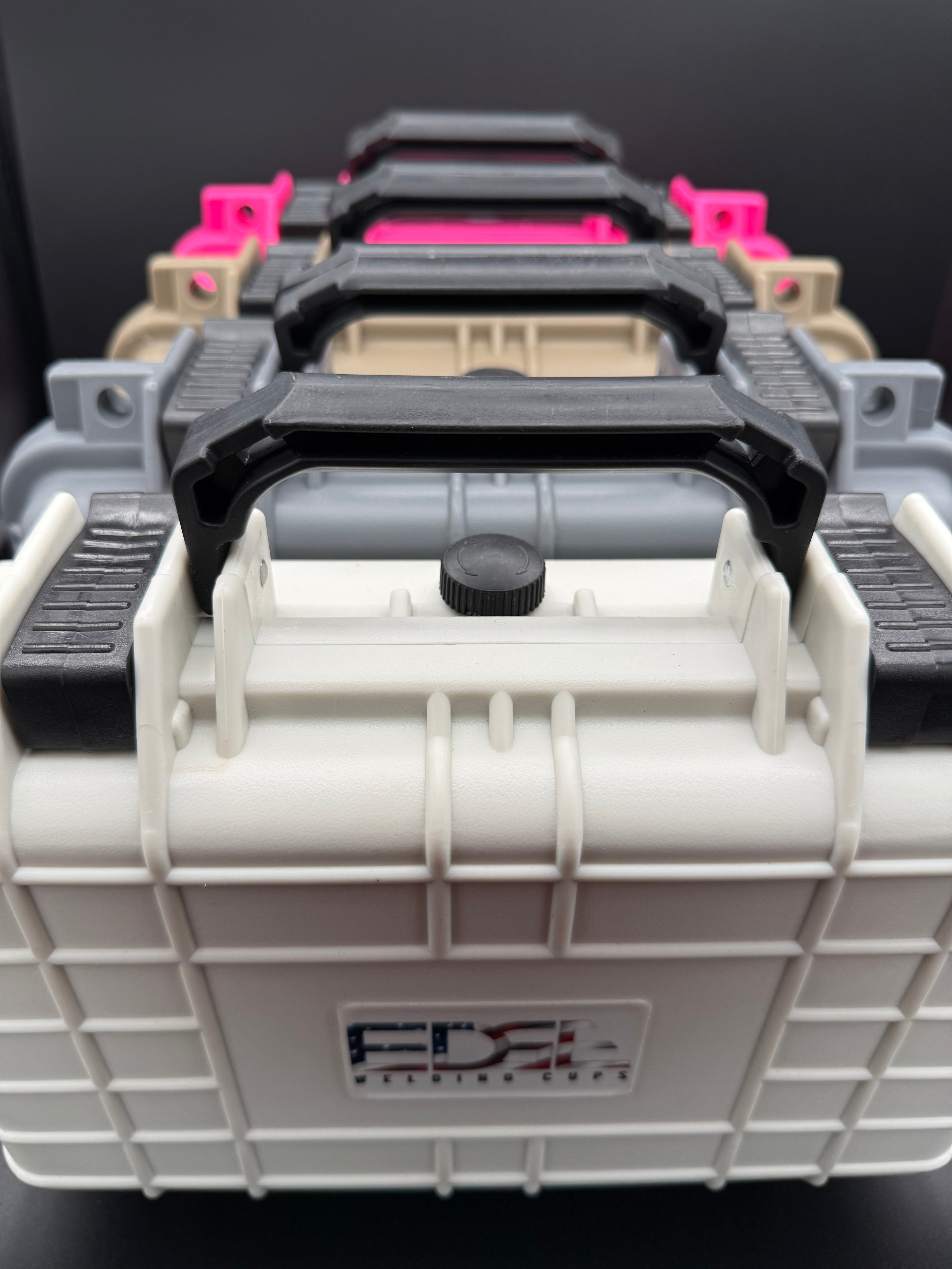 Stacked hard plastic tool cases with black handles in multiple colors, viewed close-up