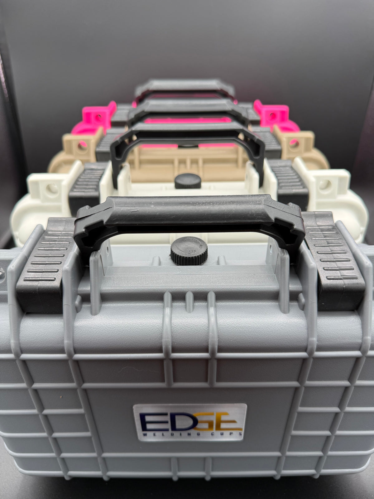Stacked protective welding supply cases with handles in various colors, front view