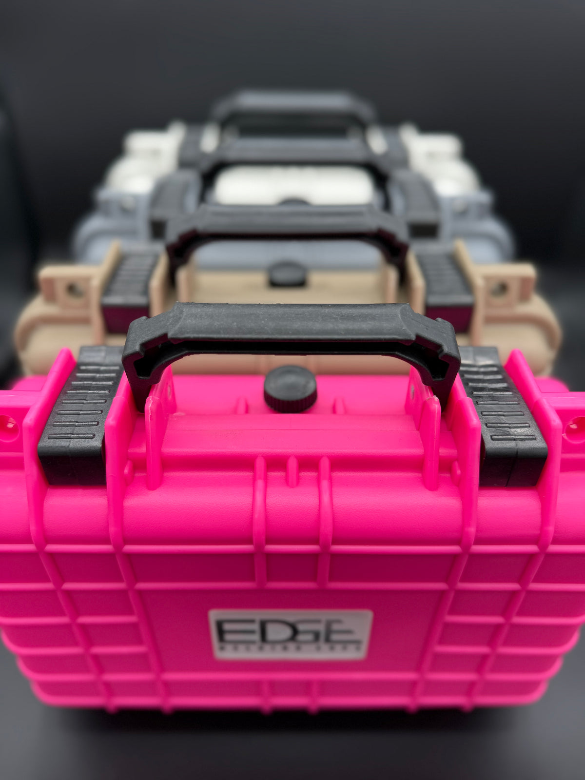 Stacked durable protective carrying cases in pink, tan, gray, and white on black background