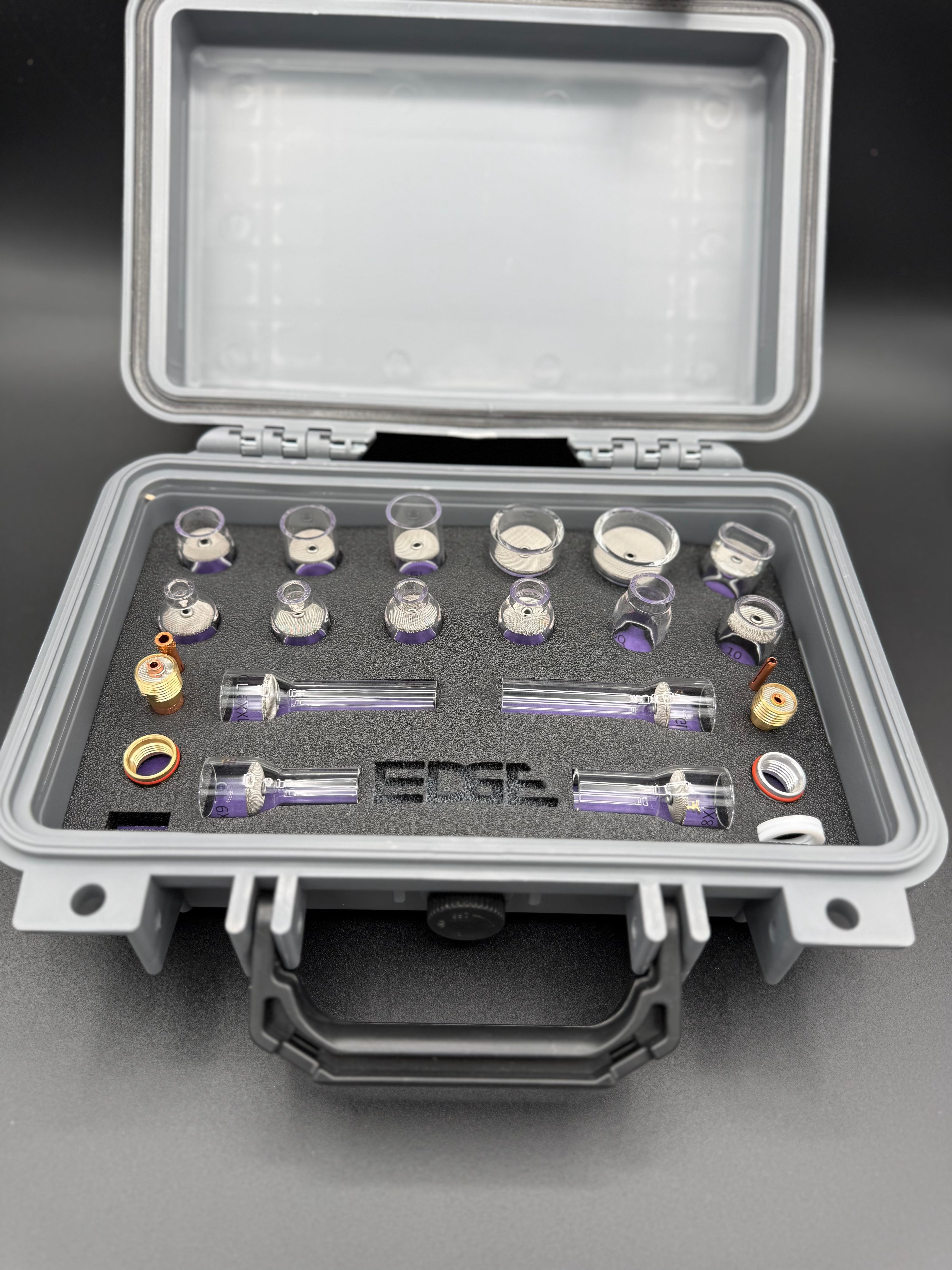 Welding cup kit with glass cups and metal fittings arranged in a foam case
