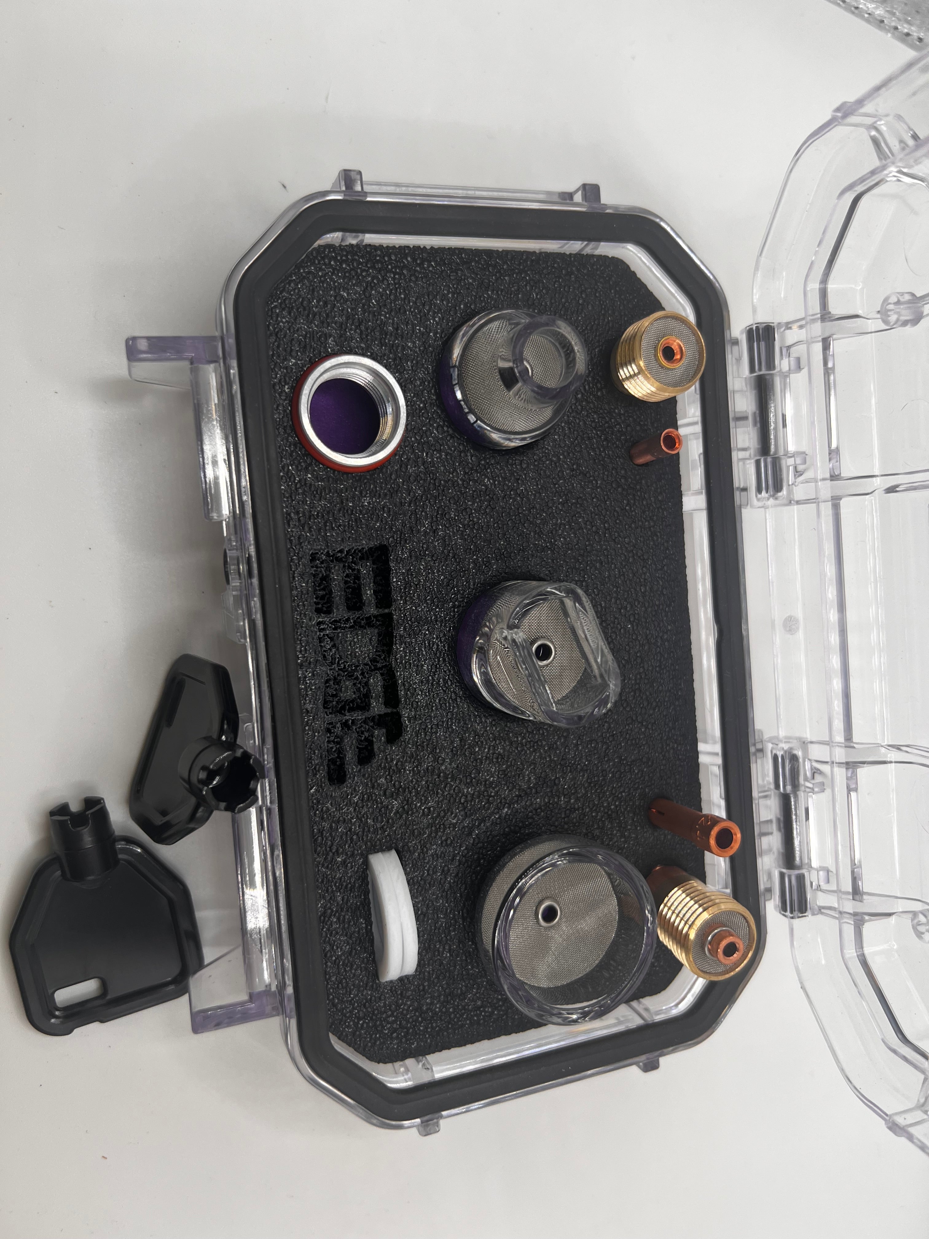 Protective case with assorted metal and plastic vape accessories on black foam insert